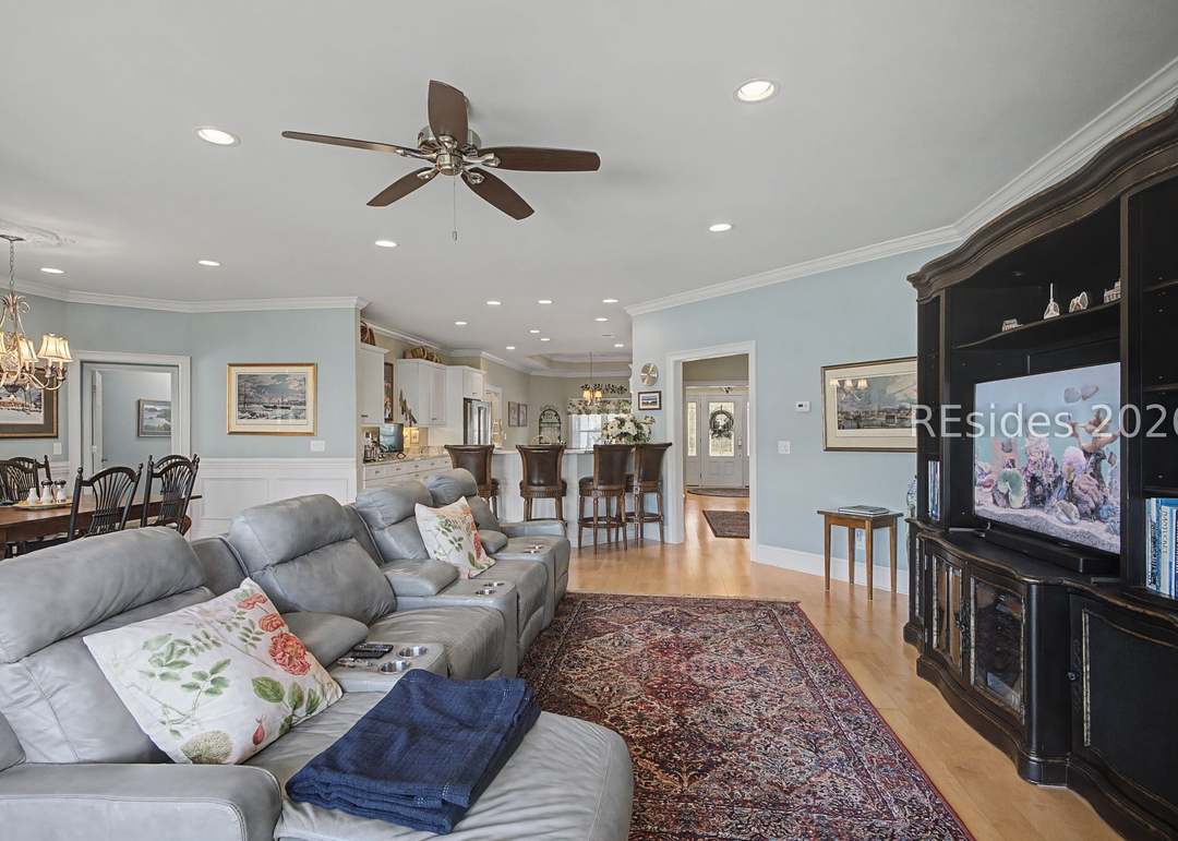 Open great room with cathedral ceiling, light blue walls, oversized sectional sofa, antique Persian rug and view through to the kitchen and dining beyond