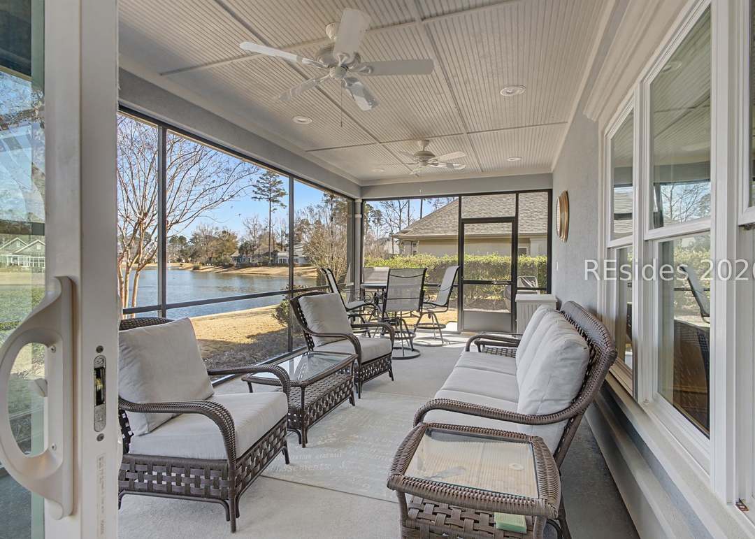 Screened lanai of 40 Catamaran with wicker seating arrangement, dual ceiling fans, a low coffee table and a clear view across the lagoon to the wooded far bank