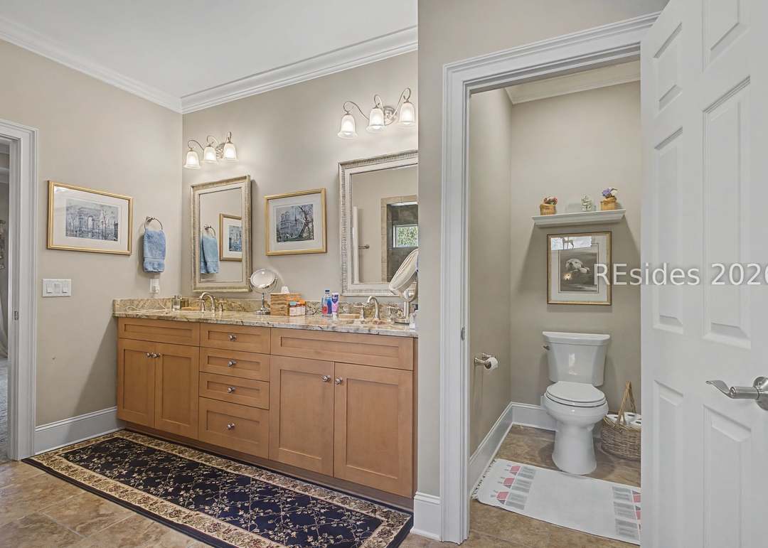 Primary bath with double granite vanity, framed mirrors, sconce lighting, a separate water closet and crown molding throughout