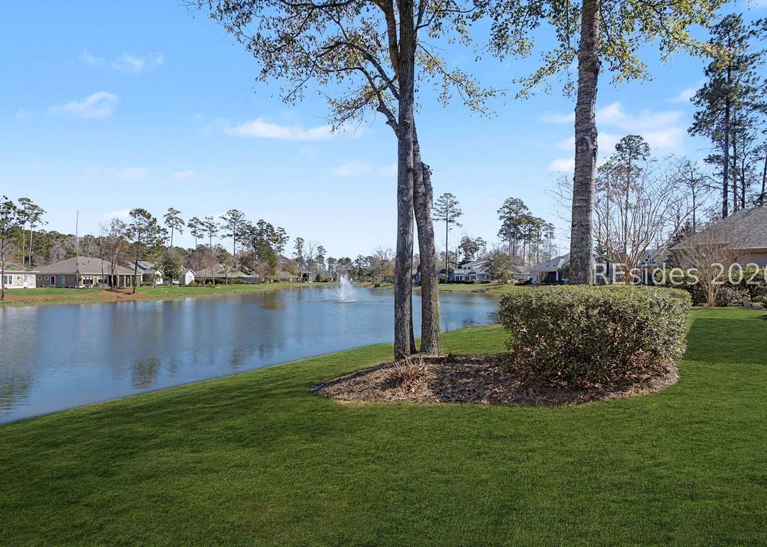 Backyard view of the lagoon from the lawn with a palm and crepe myrtle framing the central fountain across the open water